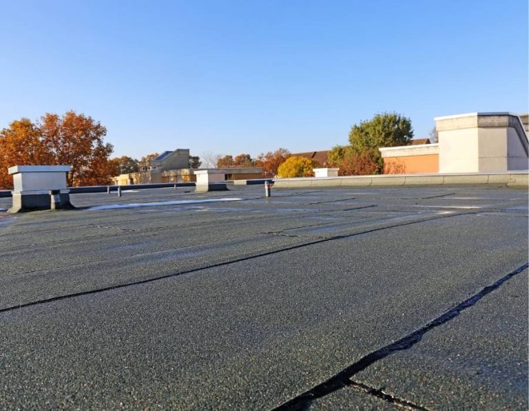 Flat commercial roof with ventilation structures and autumn trees in the background, highlighting rooftop planning and safety measures for commercial properties.