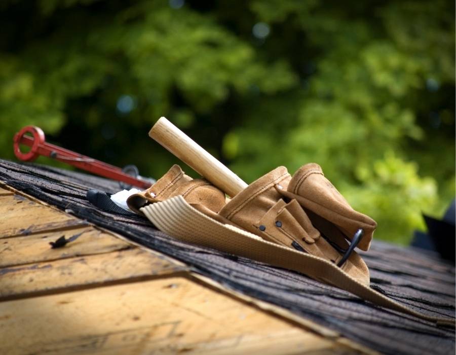 Tool belt resting on a roof under construction, symbolizing the decision between DIY roof repair and hiring a professional roofing company.