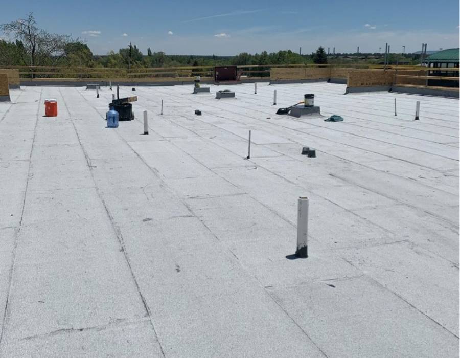 White modified bitumen commercial roofing system with visible utility penetrations, designed for energy efficiency, weather resistance, and UV protection.
