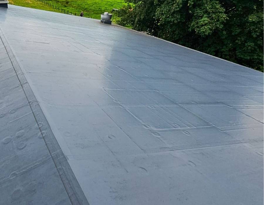 Smooth single-ply membrane roofing system on a commercial building, offering waterproof protection and energy efficiency near a green landscape.