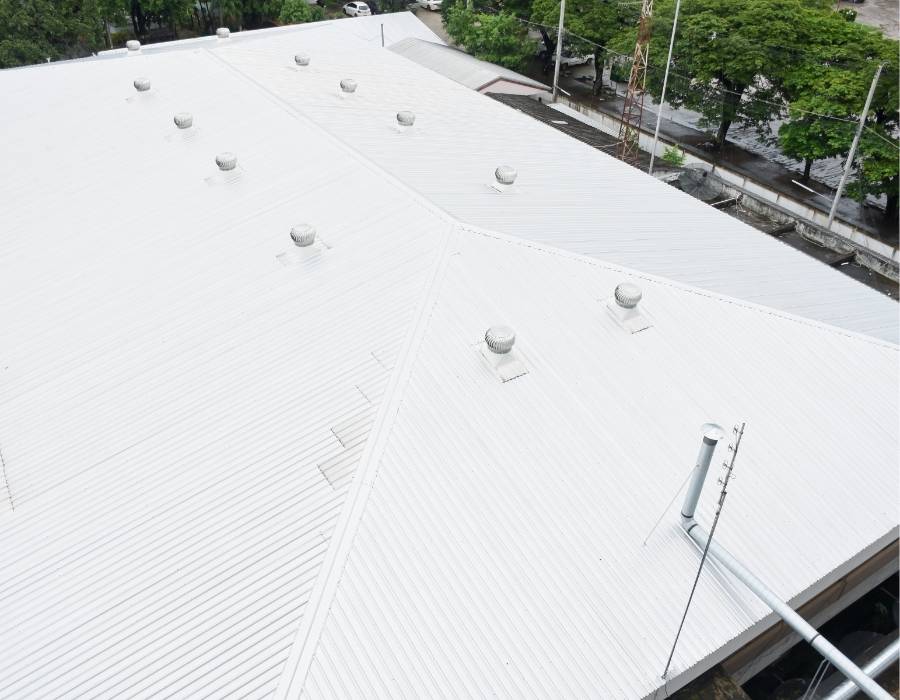 White commercial metal roof with ventilation systems on a Maryland industrial building