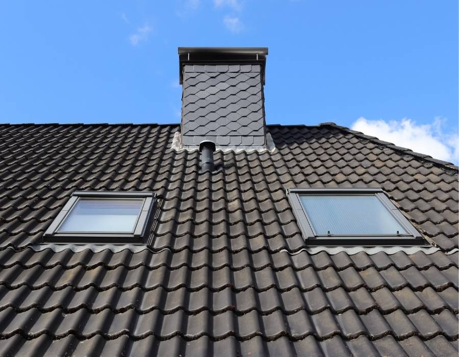 Maryland home roof with dark tile shingles, skylight windows, and chimney detail