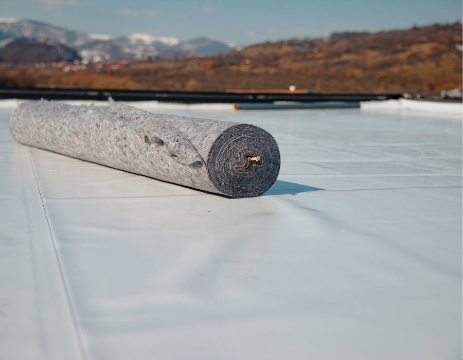 PVC roofing installation with protective underlayment roll on a flat roof in Maryland
