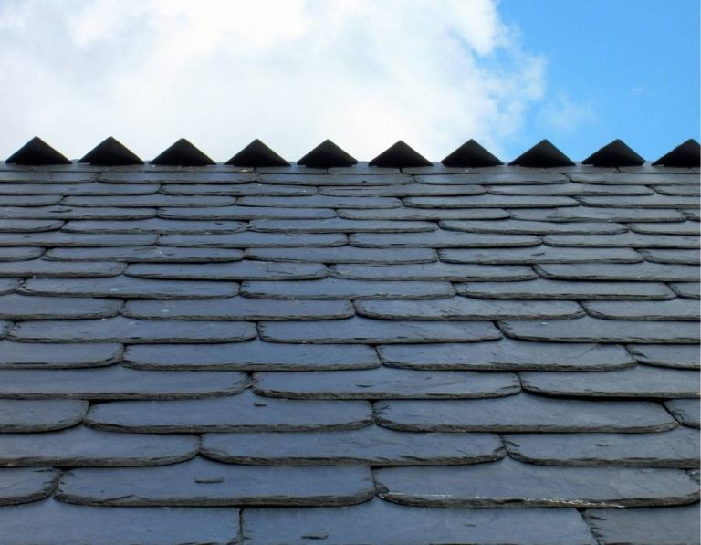 Close-up of residential slate roof shingles showing durable roofing material against blue sky