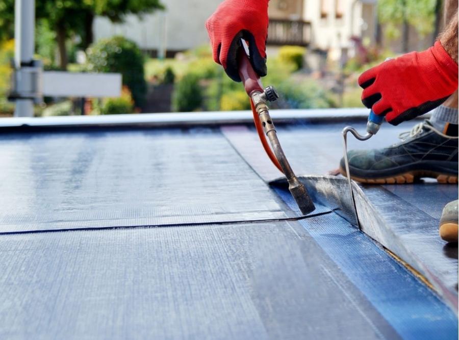 Flat roof repair with propane blowtorch during construction works with roofing felt